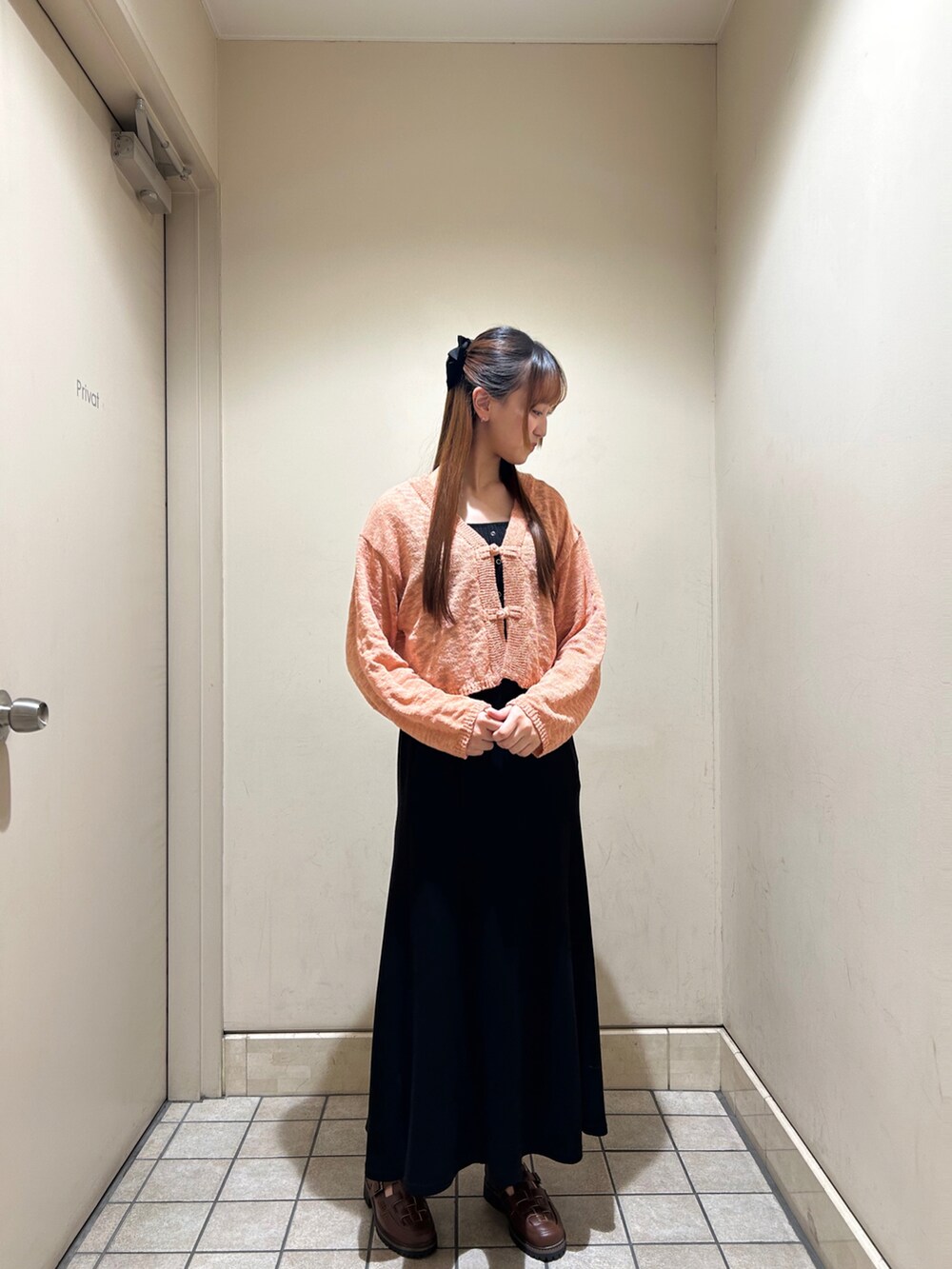 ピンク系のカーディガン/ボレロ、ブラック系のスカート、ブラウン系のサンダルを着用したレディースの春コーディネートの2枚目の写真