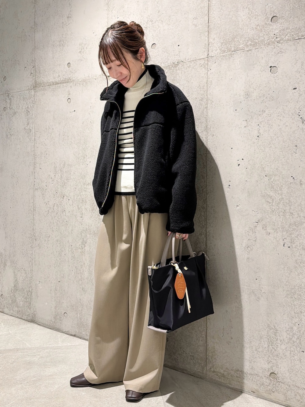 ブラック系のブルゾン、ホワイト系のニット/セーター、ベージュ系のその他パンツを着用したレディースの秋コーディネートの2枚目の写真
