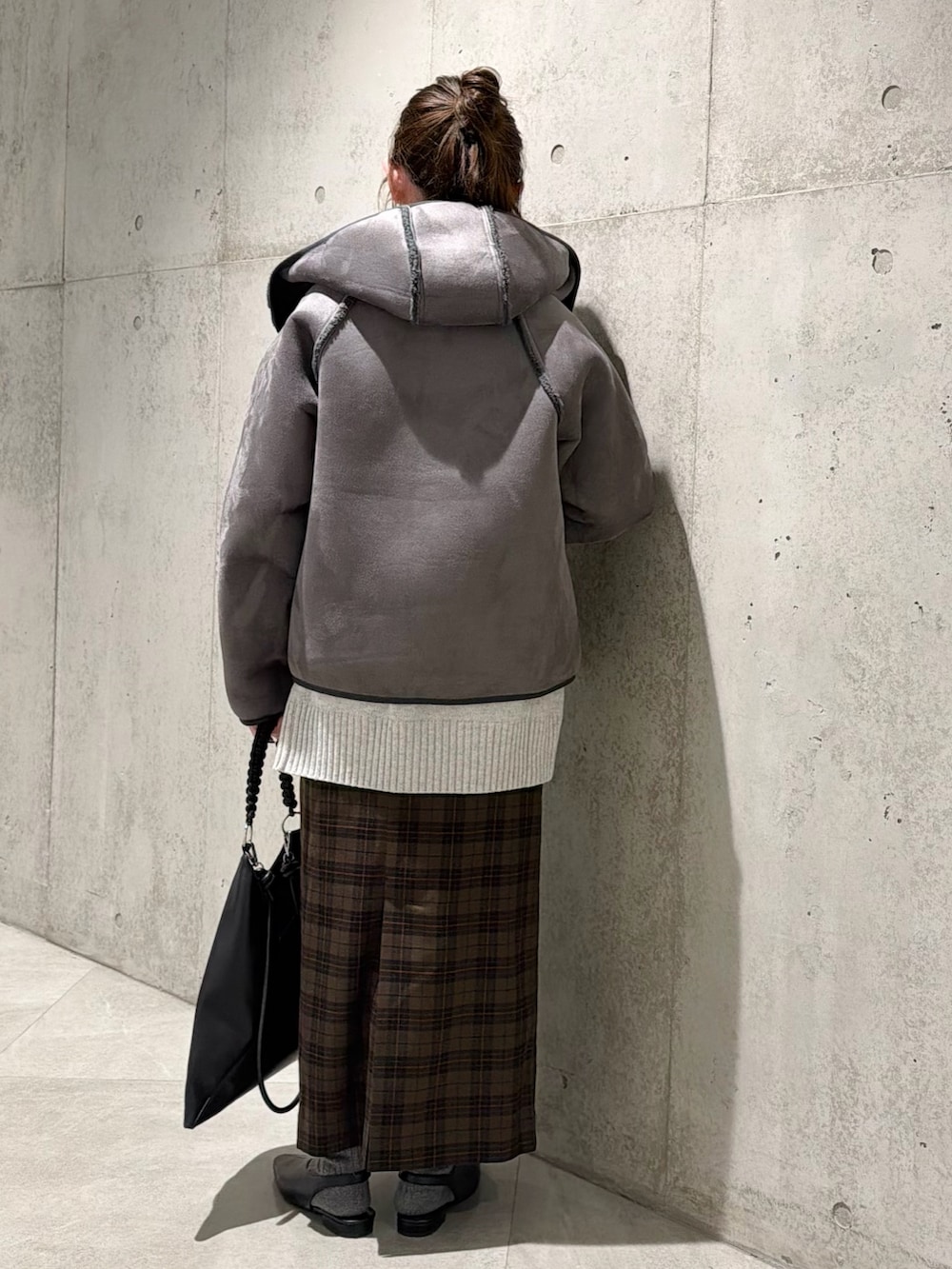 ブラック系のムートンコート、グレー系のニット/セーター、ベージュ系のスカートを着用したレディースの秋コーディネートの4枚目の写真