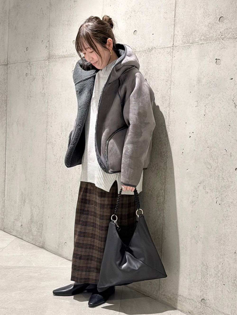 ブラック系のムートンコート、グレー系のニット/セーター、ベージュ系のスカートを着用したレディースの秋コーディネートの3枚目の写真