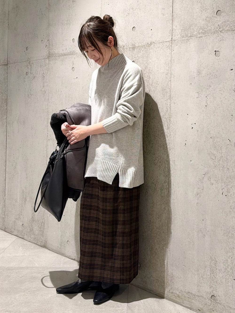 ブラック系のムートンコート、グレー系のニット/セーター、ベージュ系のスカートを着用したレディースの秋コーディネートの5枚目の写真