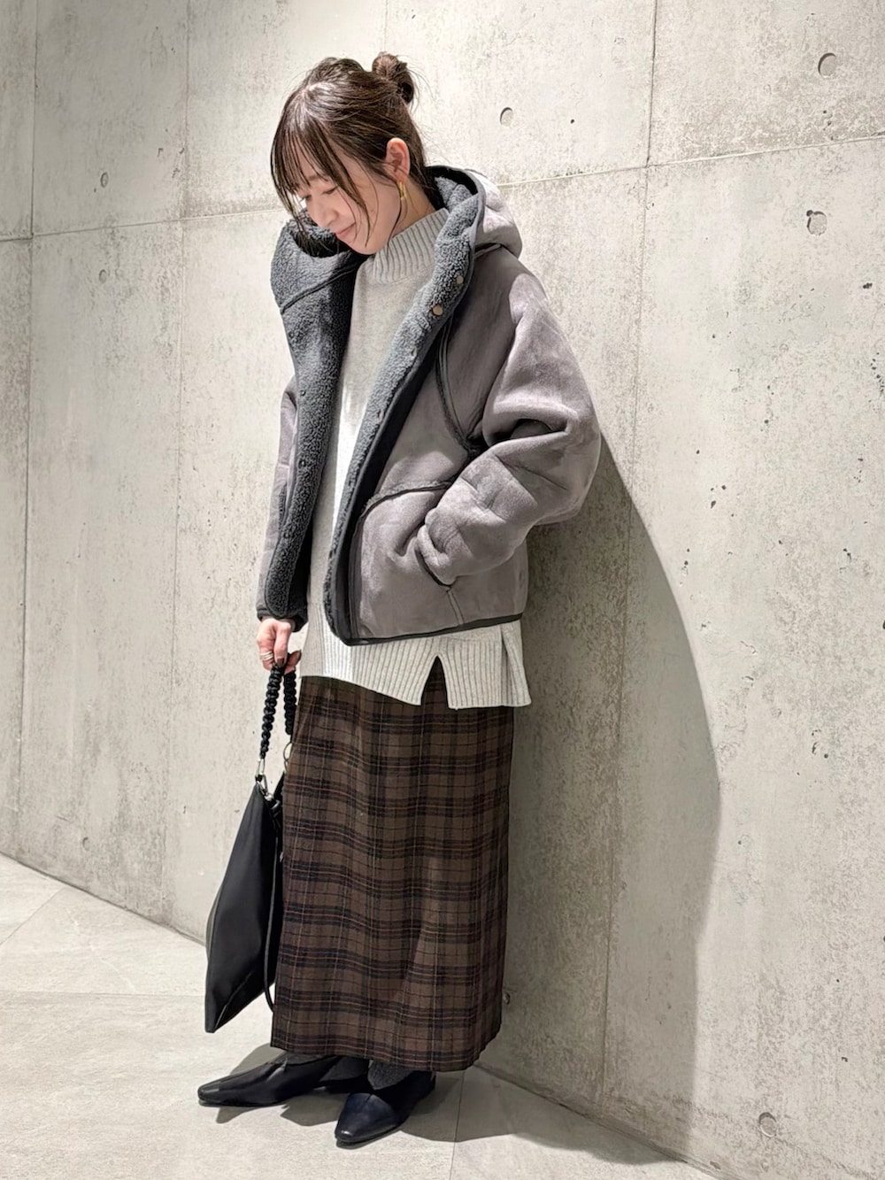 ブラック系のムートンコート、グレー系のニット/セーター、ベージュ系のスカートを着用したレディースの秋コーディネートの2枚目の写真
