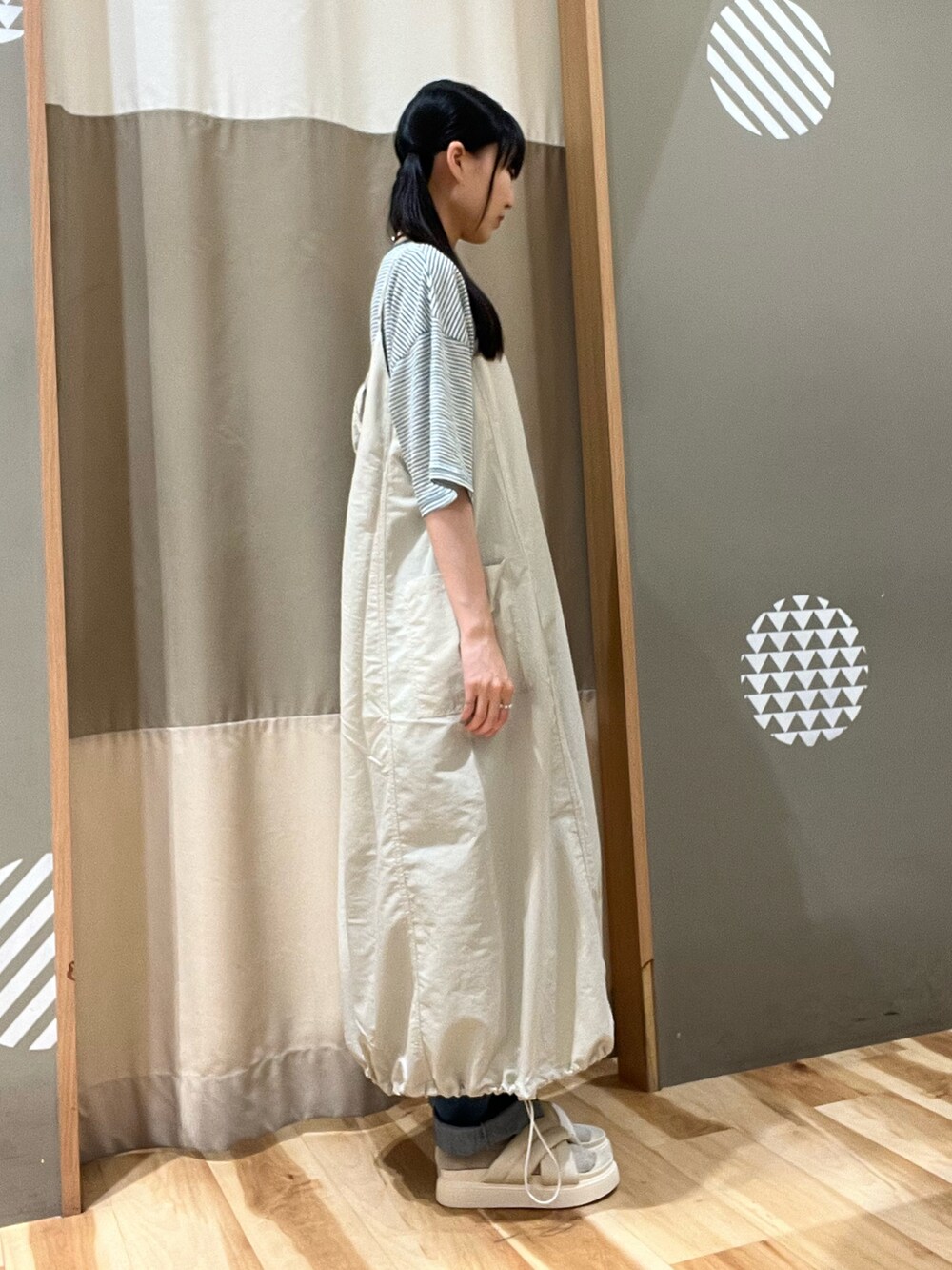 ゴールド系のハンドバッグ、ホワイト系のサンダル、グリーン系のTシャツ/カットソーを着用したレディースの夏コーディネートの2枚目の写真