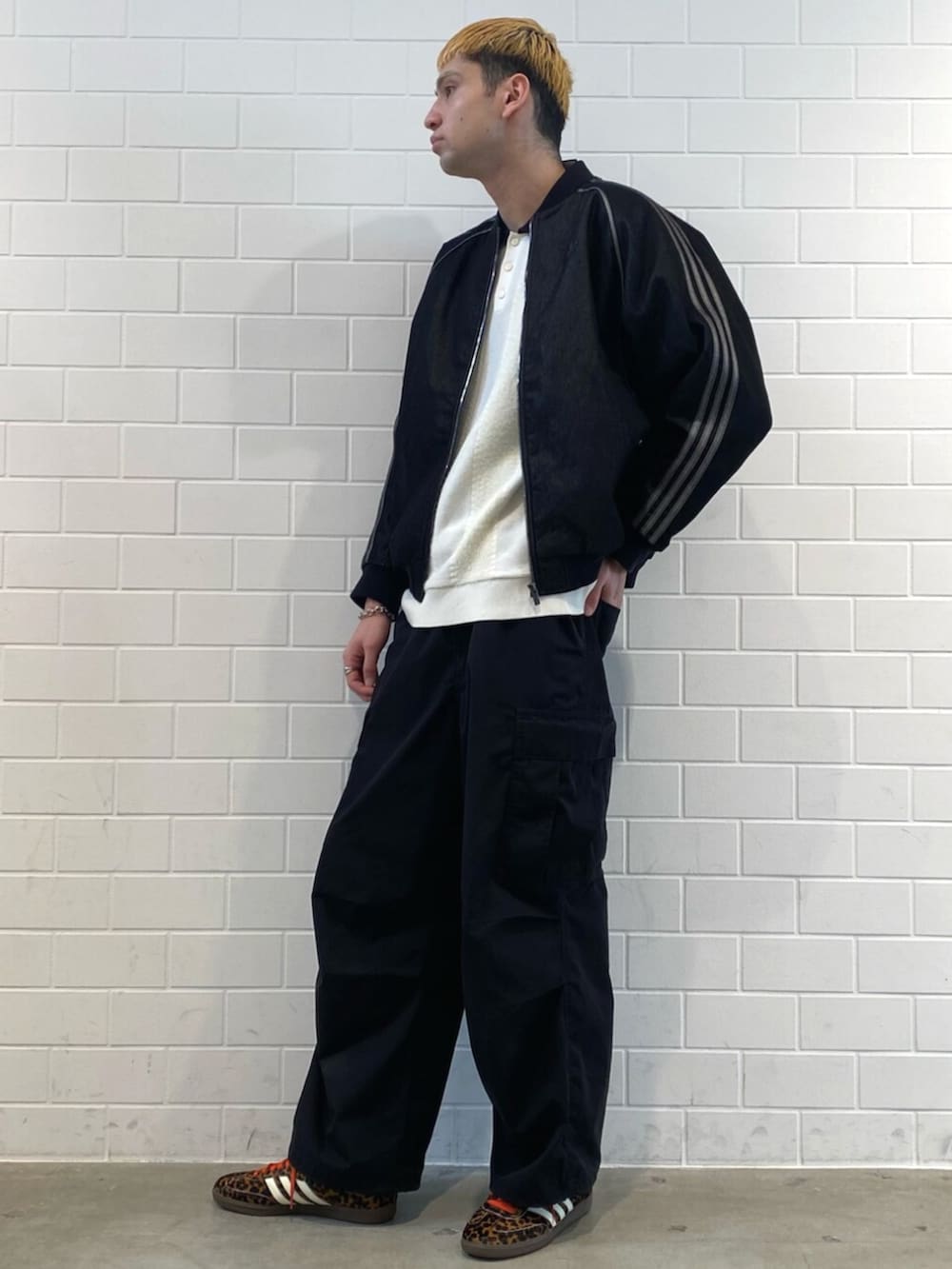 ブラック系のスニーカー、ホワイト系のニット/セーター、ブラック系のデニムジャケットを着用したメンズの秋コーディネートの3枚目の写真