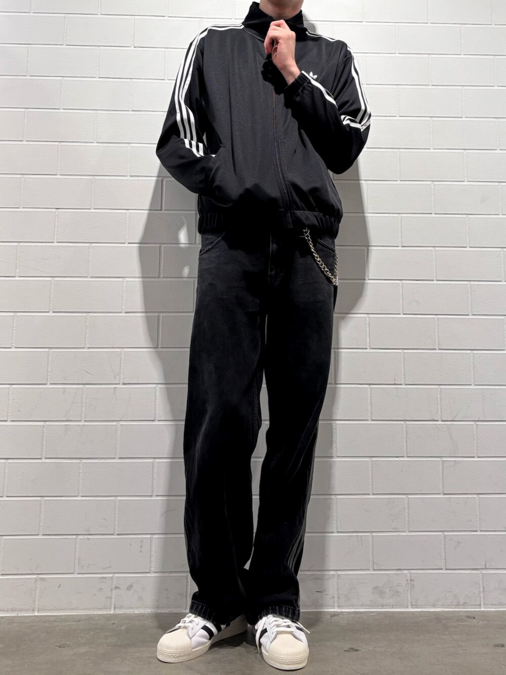 ブラック系のデニムパンツ、ホワイト系のシューズ、ブラック系のジャージを着用したメンズの秋コーディネートの2枚目の写真