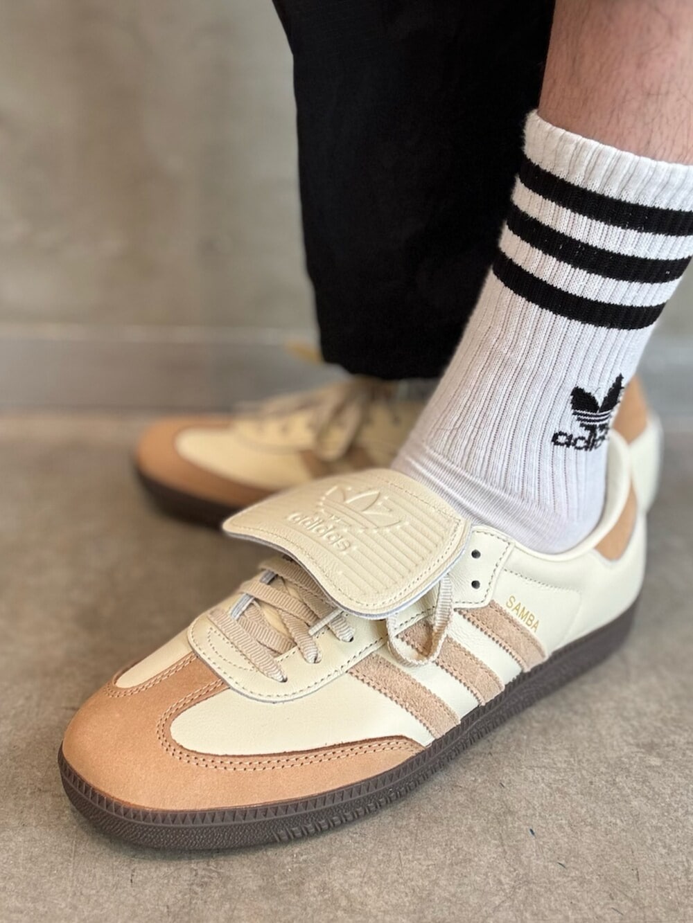 ホワイト系のスニーカー、ブラウン系のナイロンジャケット、ブラック系のその他パンツを着用したメンズの春コーディネートの6枚目の写真