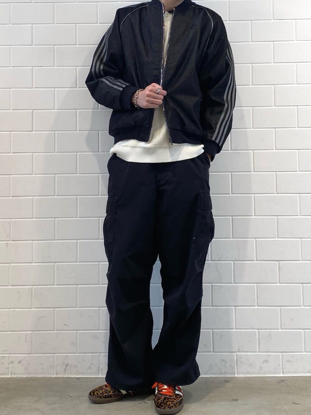 ブラック系のスニーカー、ホワイト系のニット/セーター、ブラック系のデニムジャケットを着用したメンズの秋コーディネートの2枚目の写真