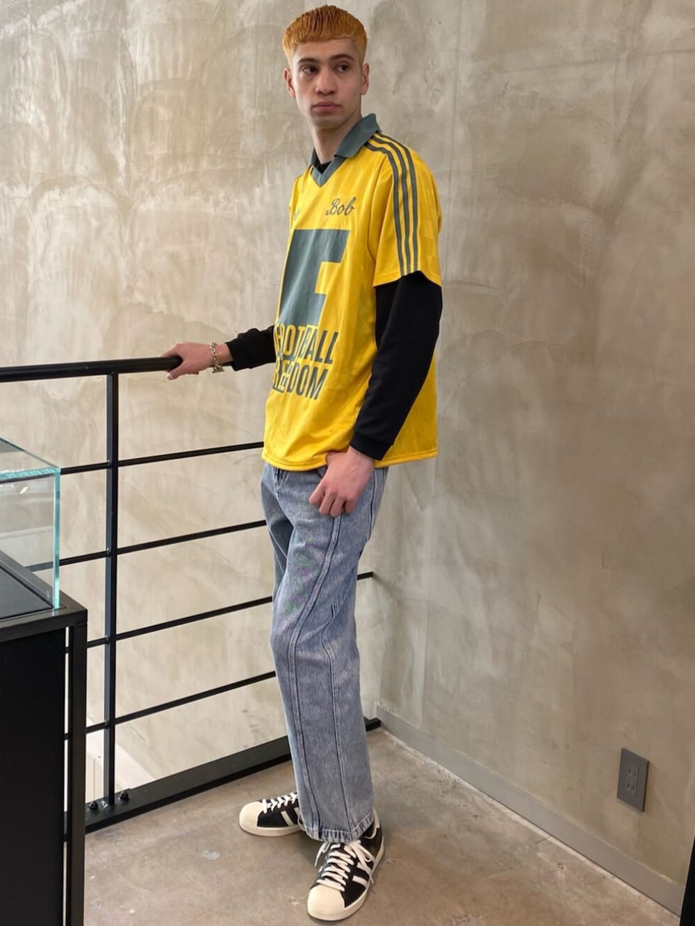 ブラック系のシューズ、グレー系のデニムパンツ、イエロー系のトップスを着用したメンズの冬コーディネートの3枚目の写真