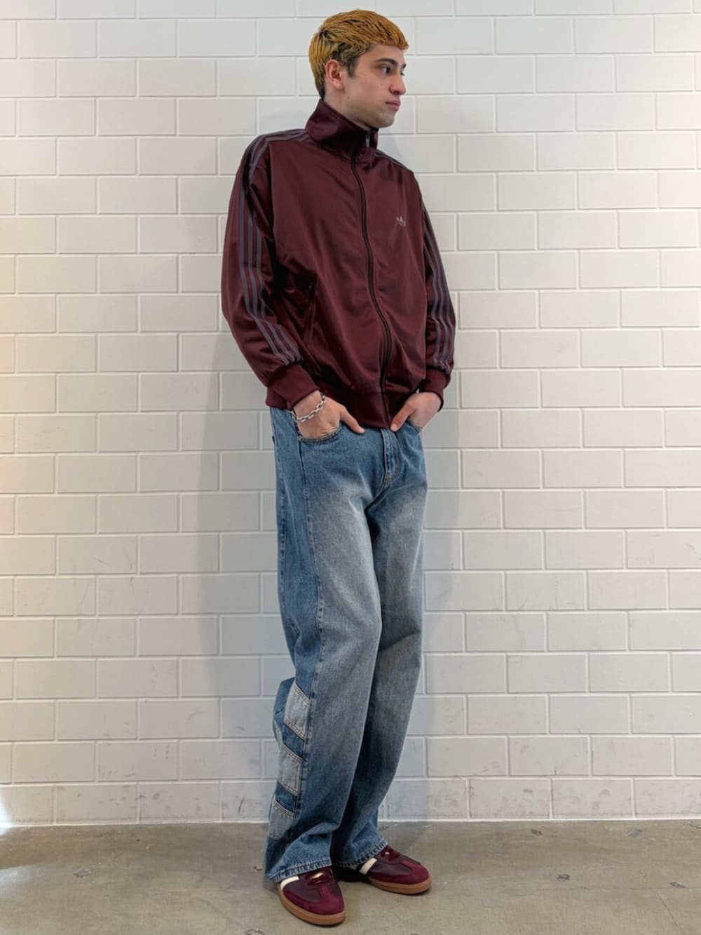 ブラウン系のスニーカー、ブルー系のデニムパンツ、レッド系のジャージを着用したメンズの春コーディネートの3枚目の写真