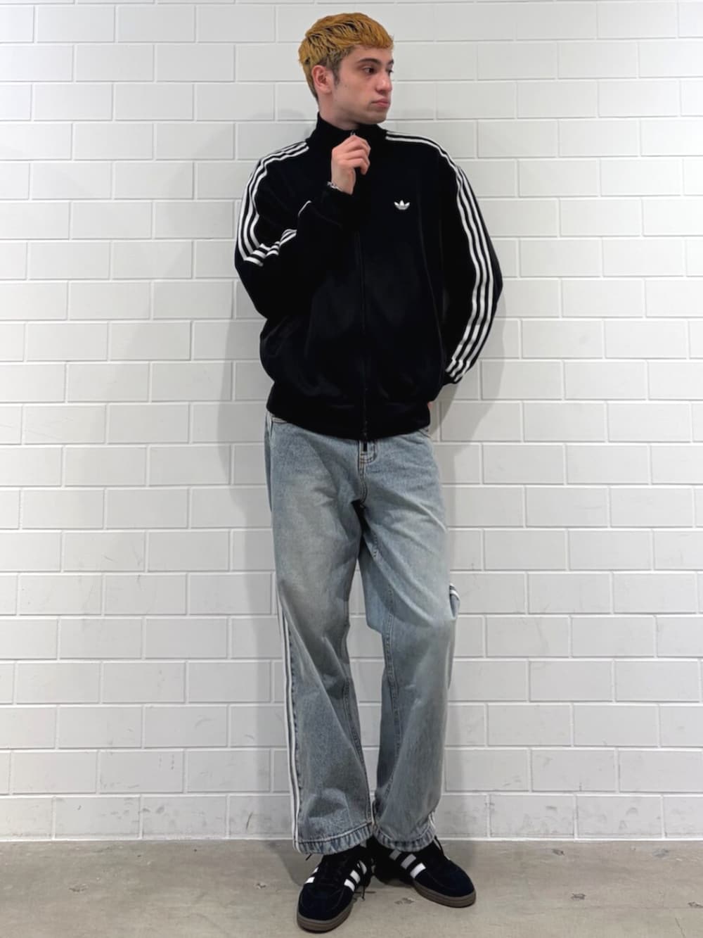 ブラック系のジャージ、ブラック系のスニーカー、ブルー系のデニムパンツを着用したメンズの春コーディネートの3枚目の写真