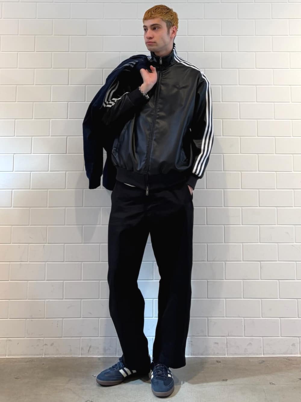 ブルー系のスニーカー、ブルー系のデニムジャケット、ブラック系のブルゾンを着用したメンズの春コーディネートの3枚目の写真