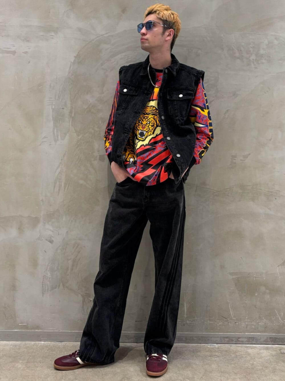 レッド系のスニーカー、ブラック系のデニムジャケット、ブラック系のデニムパンツを着用したメンズの冬コーディネートの3枚目の写真