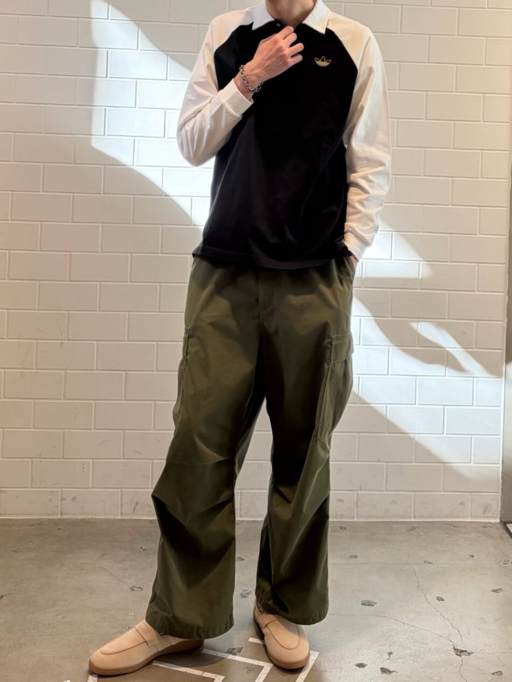 ブラック系のポロシャツ、ベージュ系のスニーカーを着用したメンズの冬コーディネートの2枚目の写真