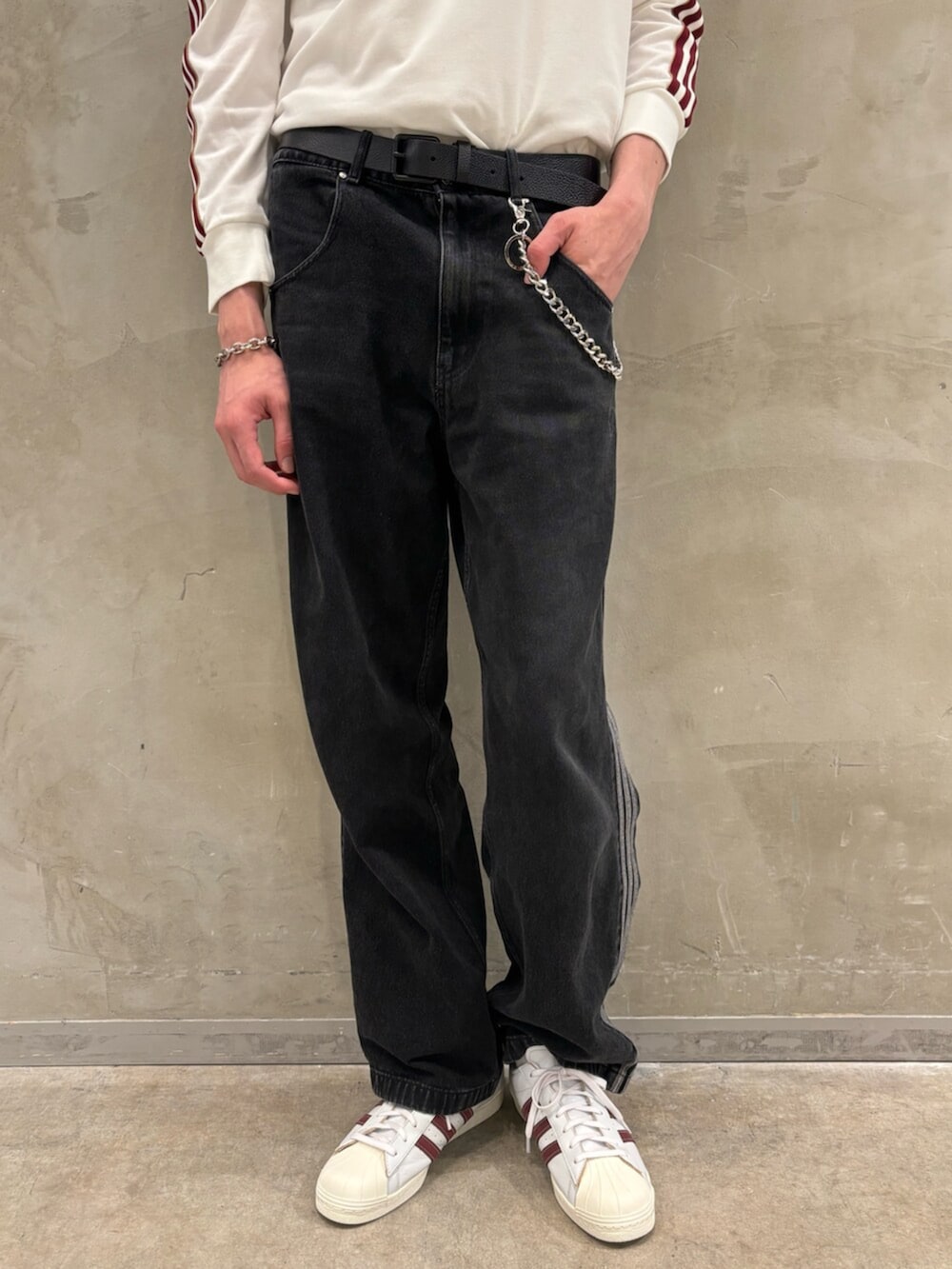 ブラック系のデニムパンツ、ホワイト系のスニーカー、ホワイト系のポロシャツを着用したメンズの夏コーディネートの5枚目の写真