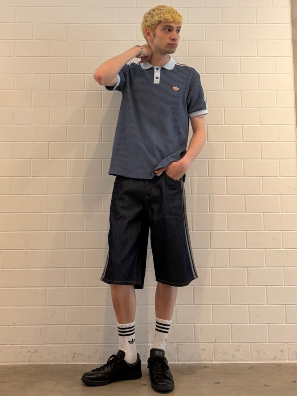 ブラック系のスニーカー、ブルー系のデニムパンツ、ブルー系のポロシャツを着用したメンズの夏コーディネートの3枚目の写真
