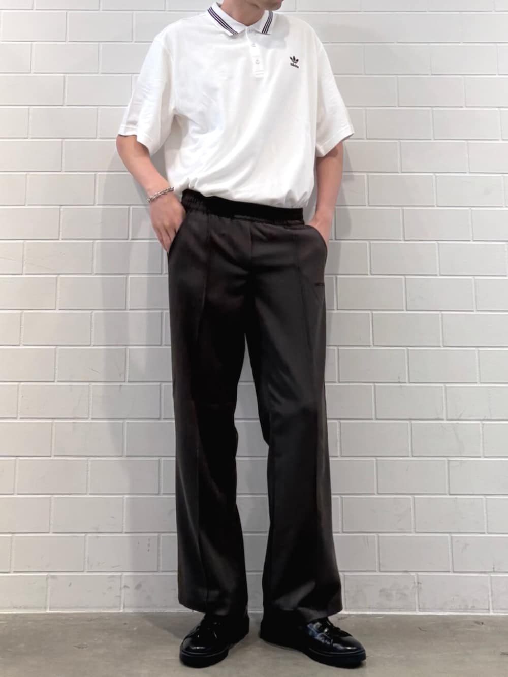 ホワイト系のポロシャツ、ブラック系のシューズ、グリーン系のスラックスを着用したメンズの秋コーディネートの2枚目の写真