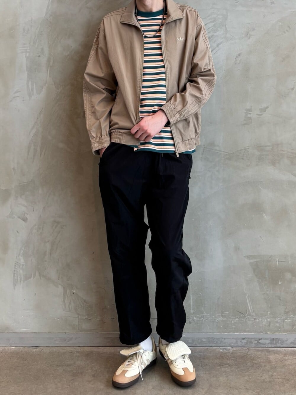 ホワイト系のスニーカー、ブラウン系のナイロンジャケット、ブラック系のその他パンツを着用したメンズの春コーディネートの2枚目の写真