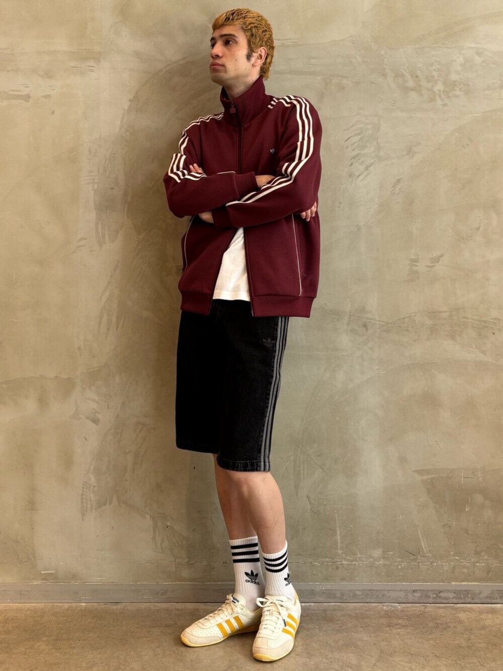 ホワイト系のスニーカー、レッド系のナイロンジャケット、ブラック系のその他パンツを着用したメンズの夏コーディネートの3枚目の写真