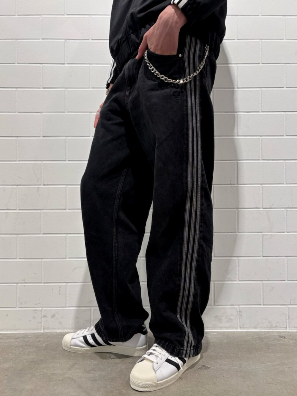 ブラック系のデニムパンツ、ホワイト系のシューズ、ブラック系のジャージを着用したメンズの秋コーディネートの5枚目の写真