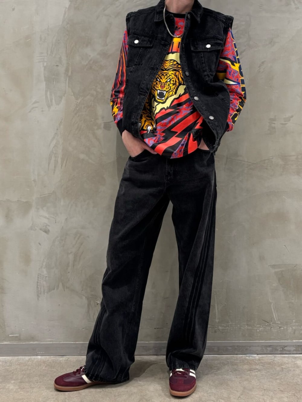 レッド系のスニーカー、ブラック系のデニムジャケット、ブラック系のデニムパンツを着用したメンズの冬コーディネートの2枚目の写真