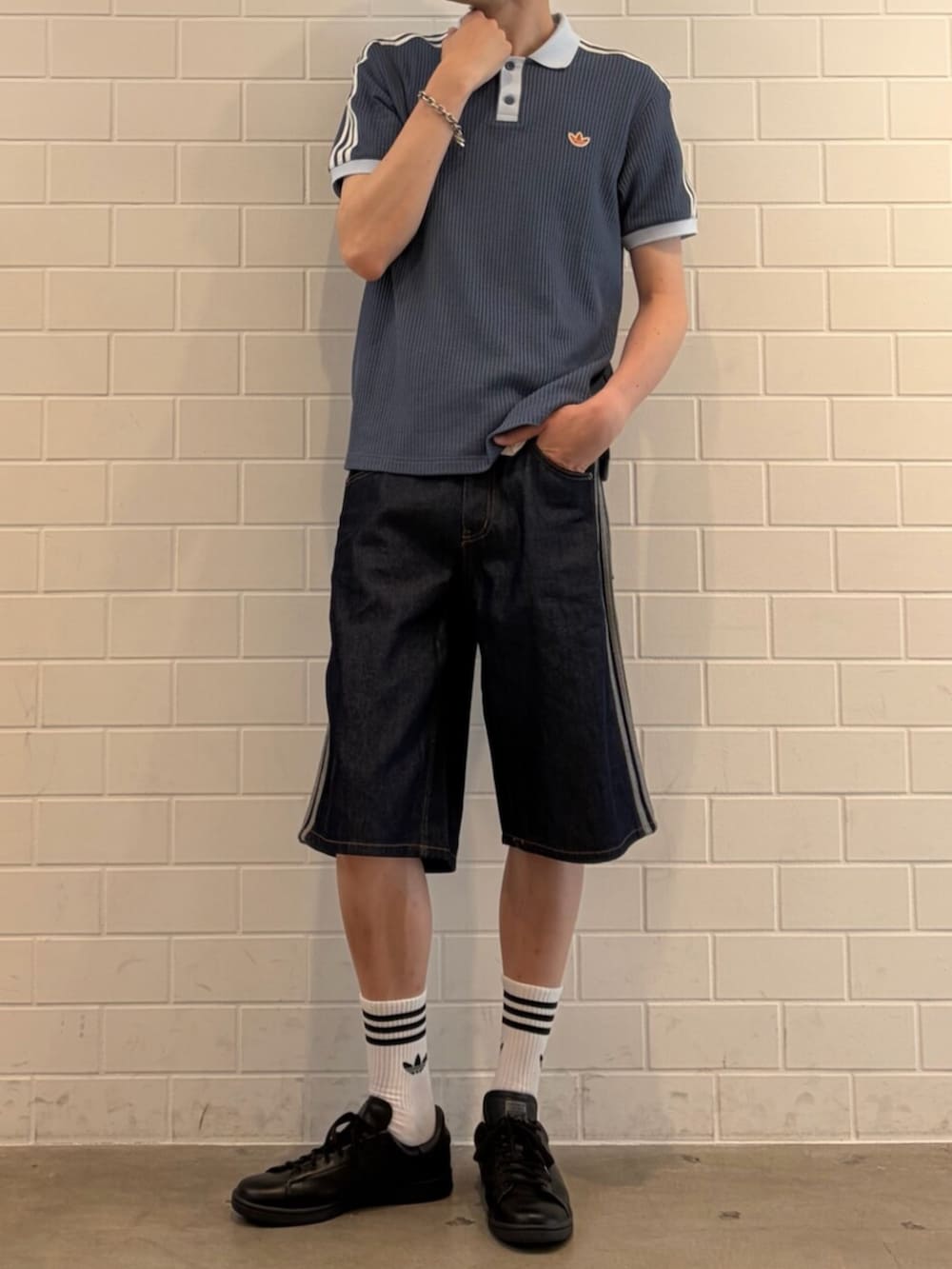 ブラック系のスニーカー、ブルー系のデニムパンツ、ブルー系のポロシャツを着用したメンズの夏コーディネートの2枚目の写真