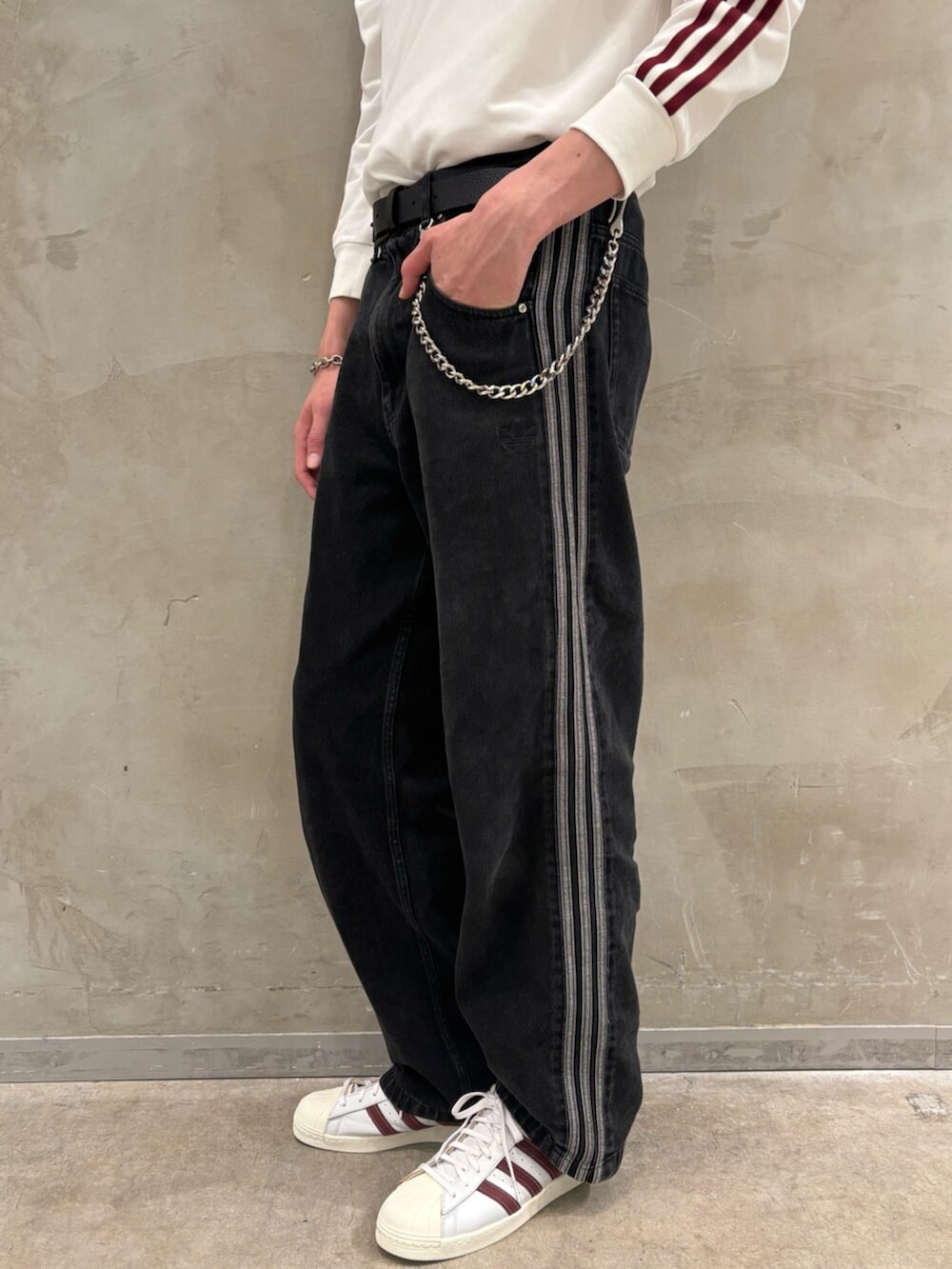 ブラック系のデニムパンツ、ホワイト系のスニーカー、ホワイト系のポロシャツを着用したメンズの夏コーディネートの4枚目の写真