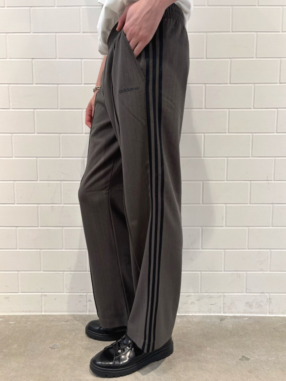 ホワイト系のポロシャツ、ブラック系のシューズ、グリーン系のスラックスを着用したメンズの秋コーディネートの5枚目の写真