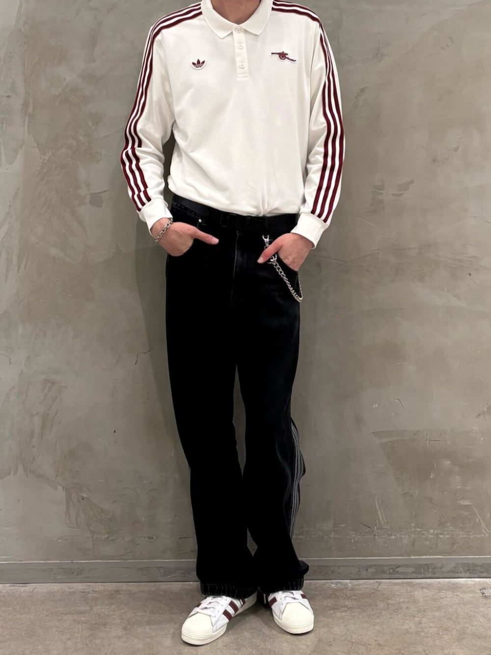 ブラック系のデニムパンツ、ホワイト系のスニーカー、ホワイト系のポロシャツを着用したメンズの夏コーディネートの2枚目の写真