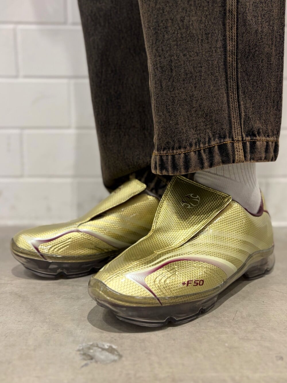 ゴールド系のシューズ、ブルー系のナイロンジャケット、ブラウン系のデニムパンツを着用したメンズの春コーディネートの6枚目の写真