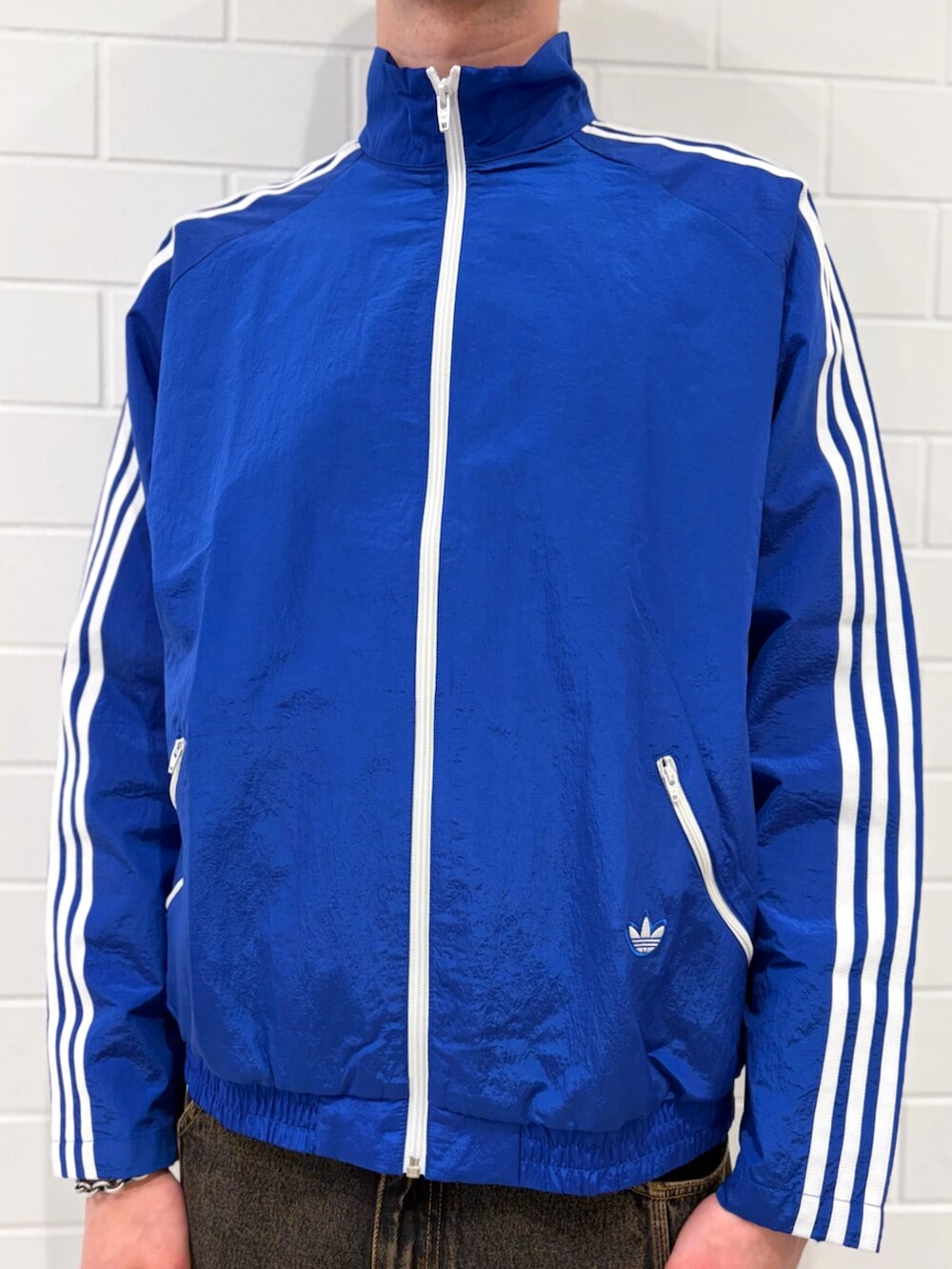 ゴールド系のシューズ、ブルー系のナイロンジャケット、ブラウン系のデニムパンツを着用したメンズの春コーディネートの4枚目の写真