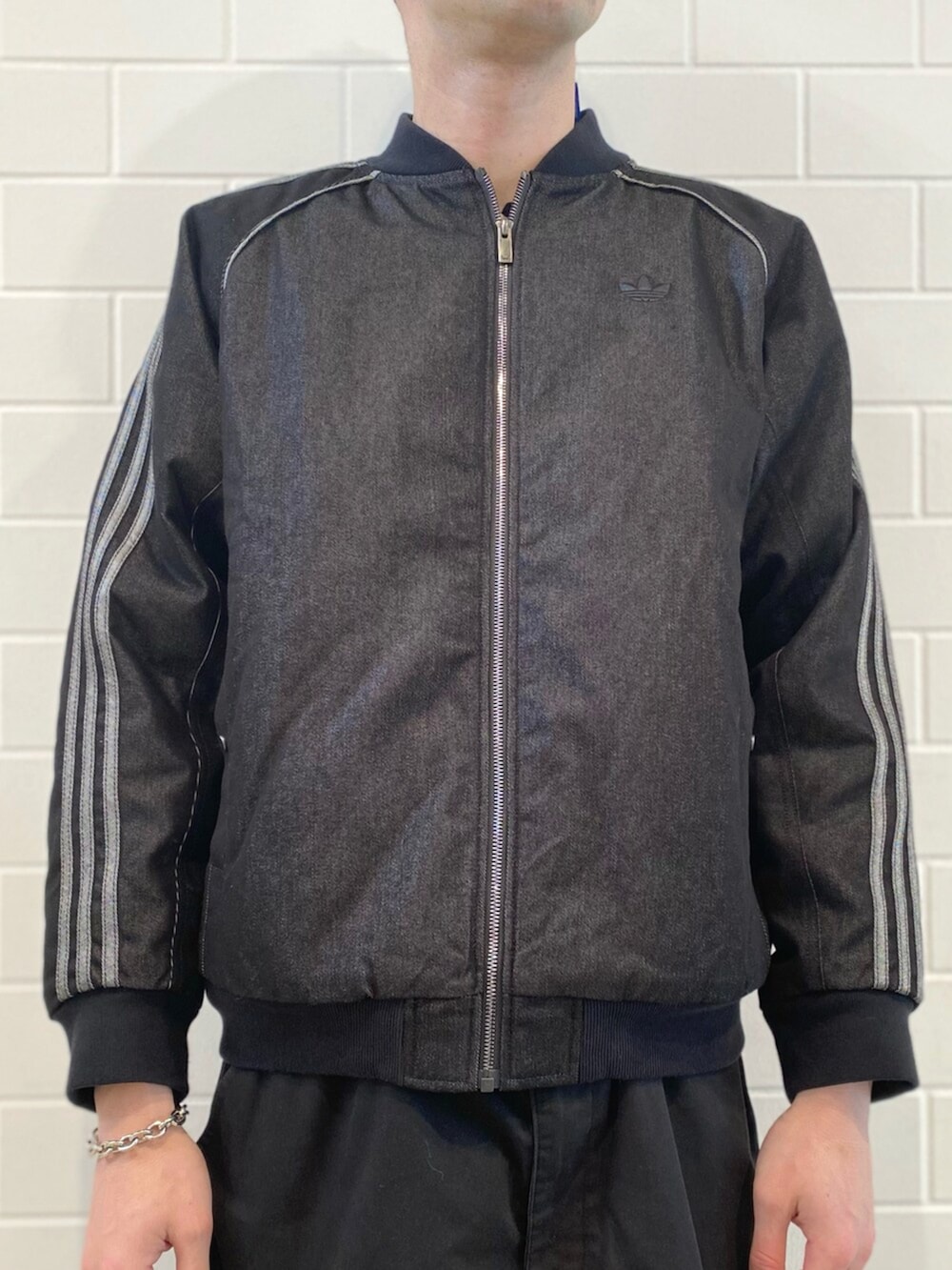 ブラック系のスニーカー、ホワイト系のニット/セーター、ブラック系のデニムジャケットを着用したメンズの秋コーディネートの4枚目の写真