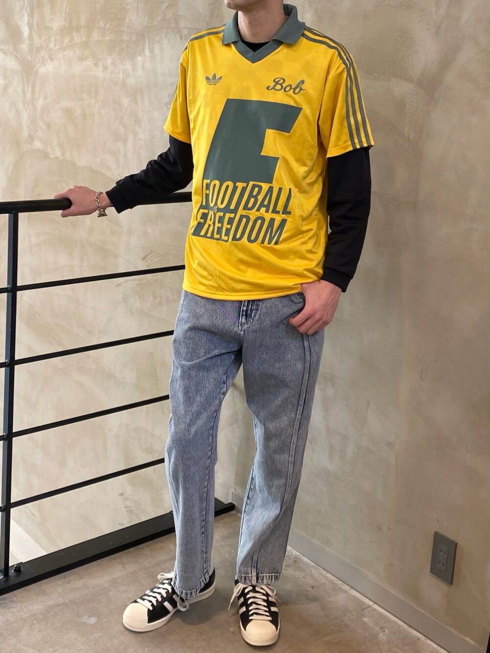 ブラック系のシューズ、グレー系のデニムパンツ、イエロー系のトップスを着用したメンズの冬コーディネートの2枚目の写真