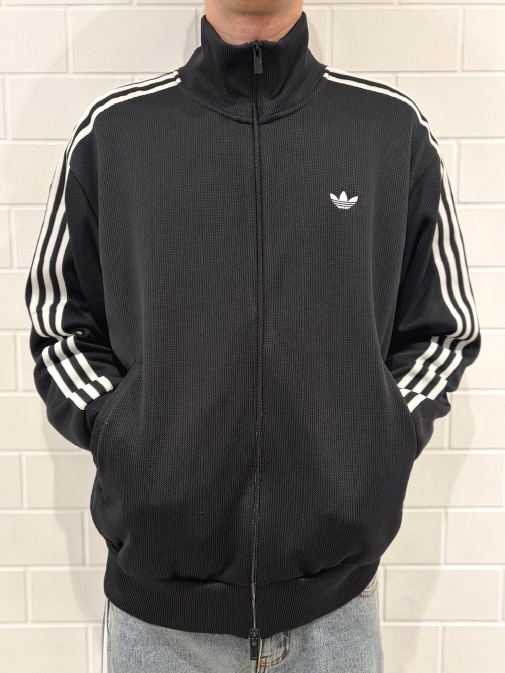 ブラック系のジャージ、ブラック系のスニーカー、ブルー系のデニムパンツを着用したメンズの春コーディネートの4枚目の写真