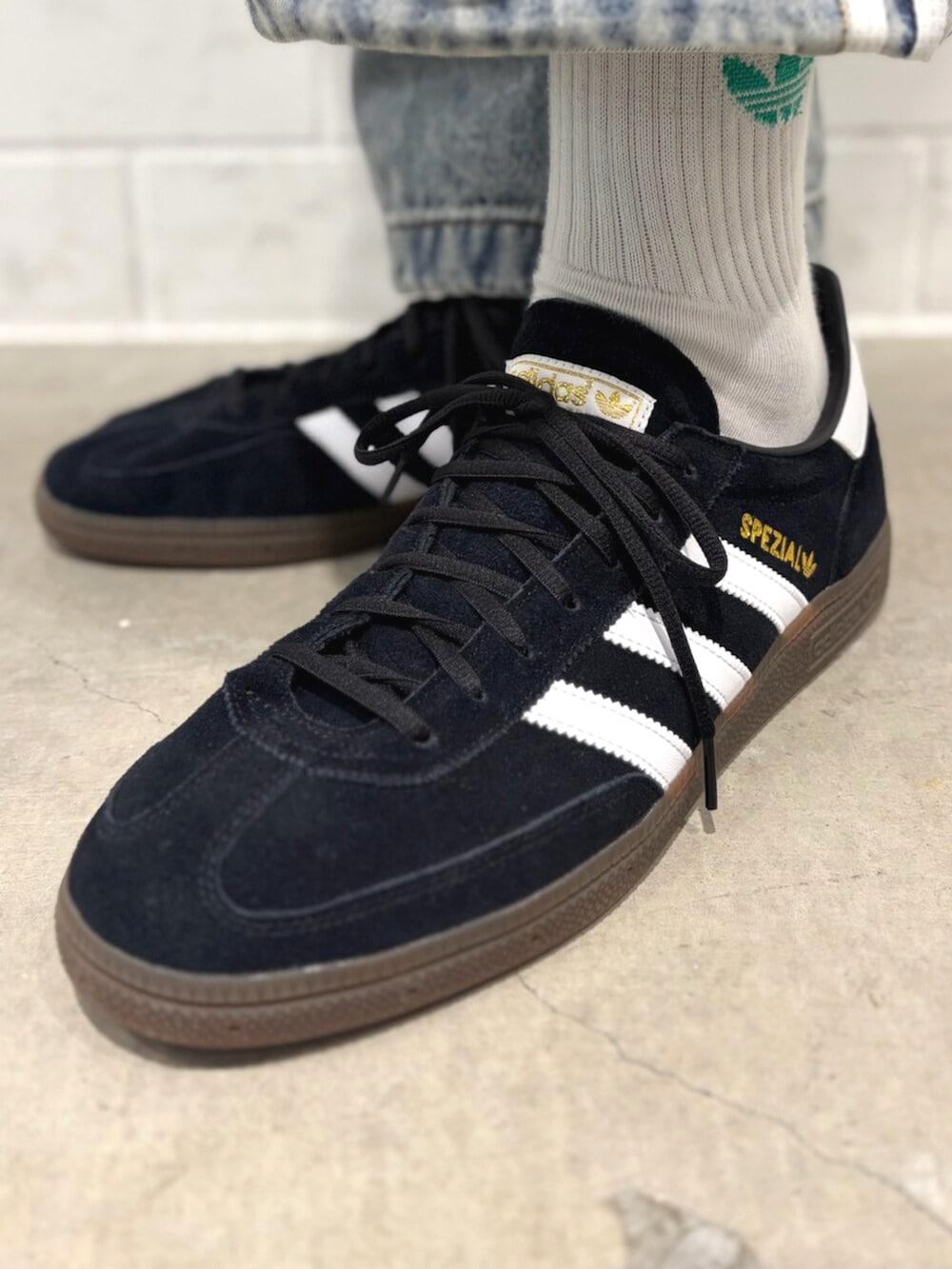 ブラック系のジャージ、ブラック系のスニーカー、ブルー系のデニムパンツを着用したメンズの春コーディネートの6枚目の写真