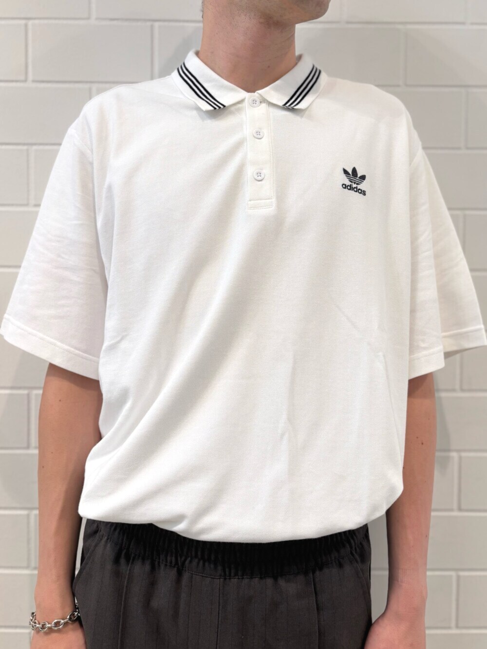 ホワイト系のポロシャツ、ブラック系のシューズ、グリーン系のスラックスを着用したメンズの秋コーディネートの4枚目の写真