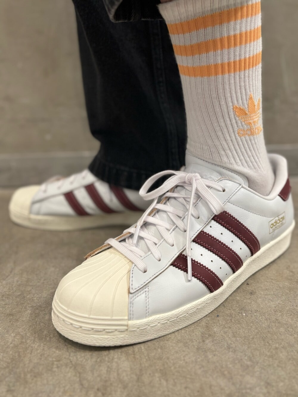 ブラック系のデニムパンツ、ホワイト系のスニーカー、ホワイト系のポロシャツを着用したメンズの夏コーディネートの6枚目の写真