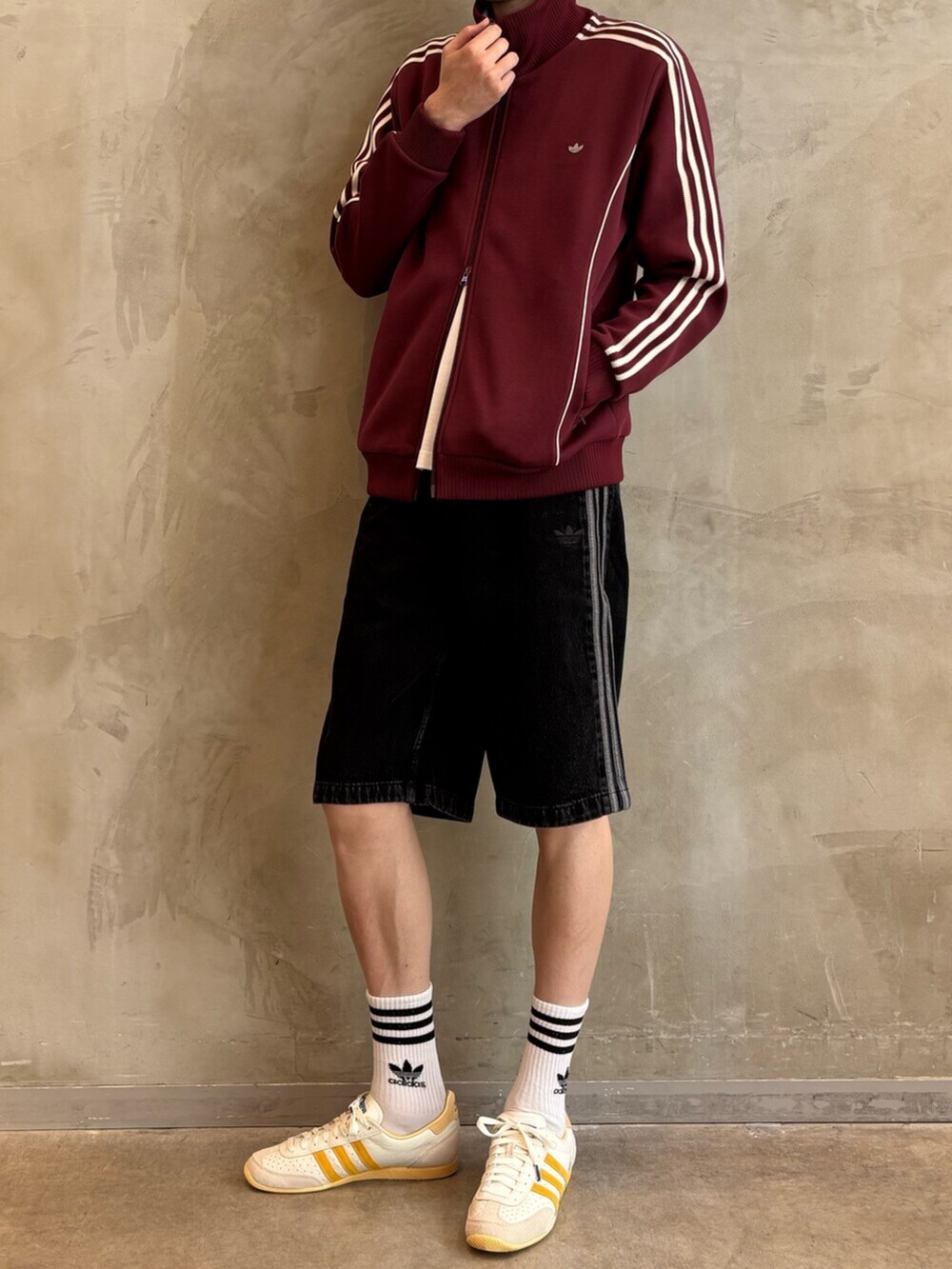 ホワイト系のスニーカー、レッド系のナイロンジャケット、ブラック系のその他パンツを着用したメンズの夏コーディネートの2枚目の写真