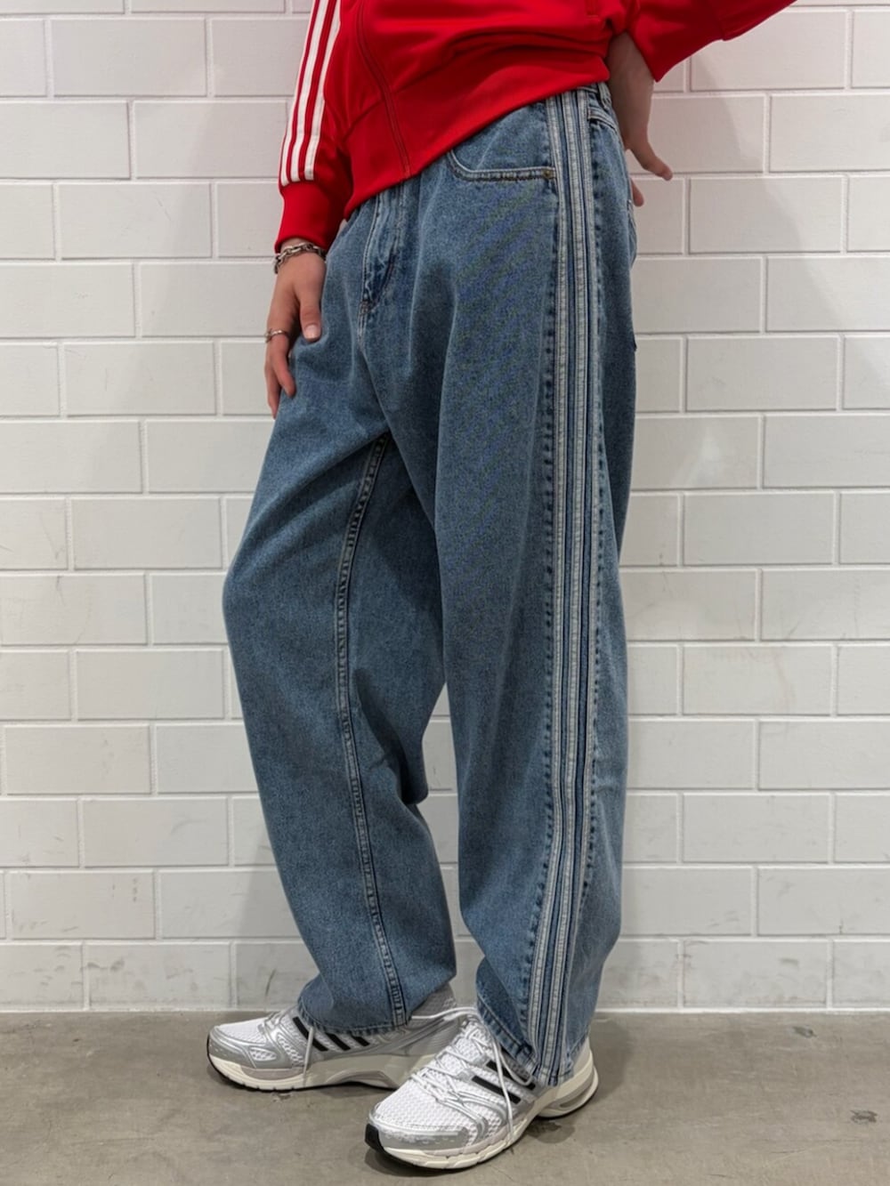 シルバー系のスニーカー、ブルー系のデニムパンツ、レッド系のジャージを着用したメンズの夏コーディネートの5枚目の写真