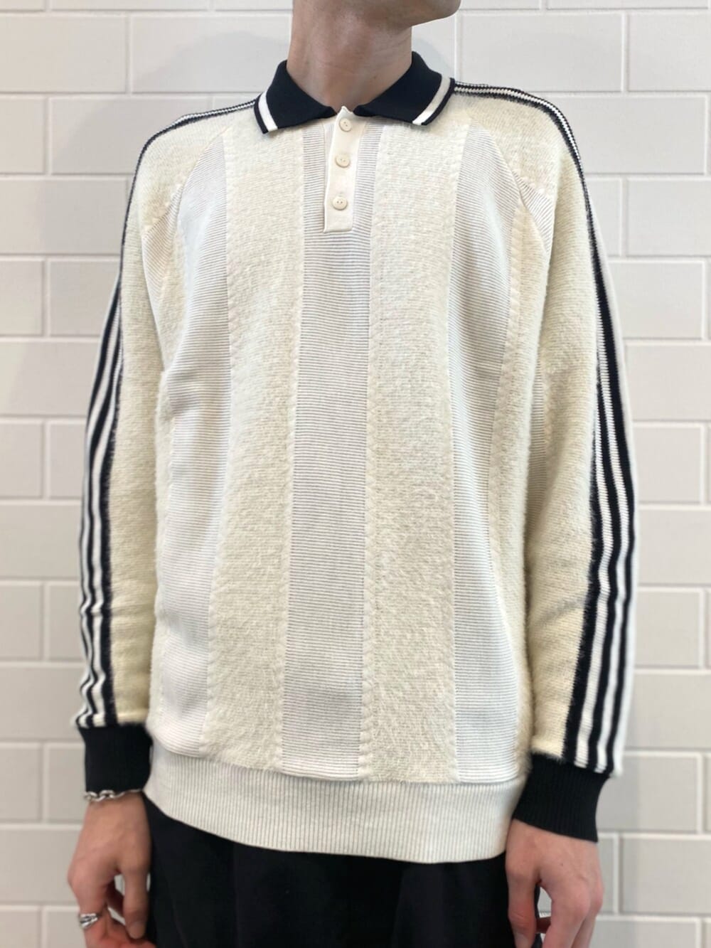 ブラック系のスニーカー、ホワイト系のニット/セーター、ブラック系のデニムジャケットを着用したメンズの秋コーディネートの5枚目の写真