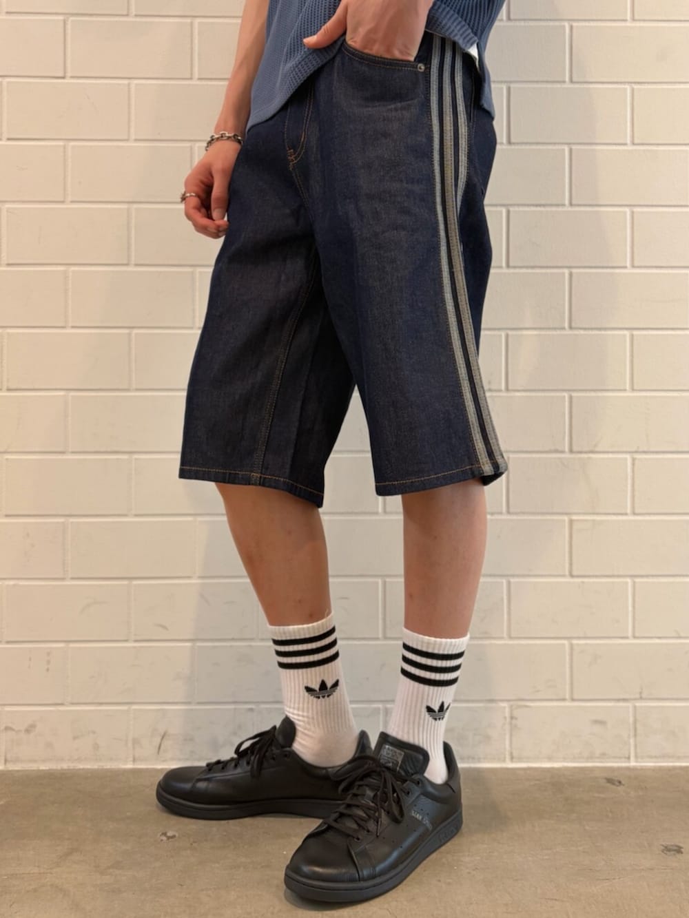 ブラック系のスニーカー、ブルー系のデニムパンツ、ブルー系のポロシャツを着用したメンズの夏コーディネートの5枚目の写真