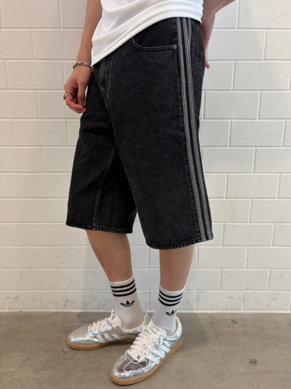 シルバー系のスニーカー、ブラック系のデニムパンツ、ホワイト系のTシャツ/カットソーを着用したメンズの夏コーディネートの5枚目の写真