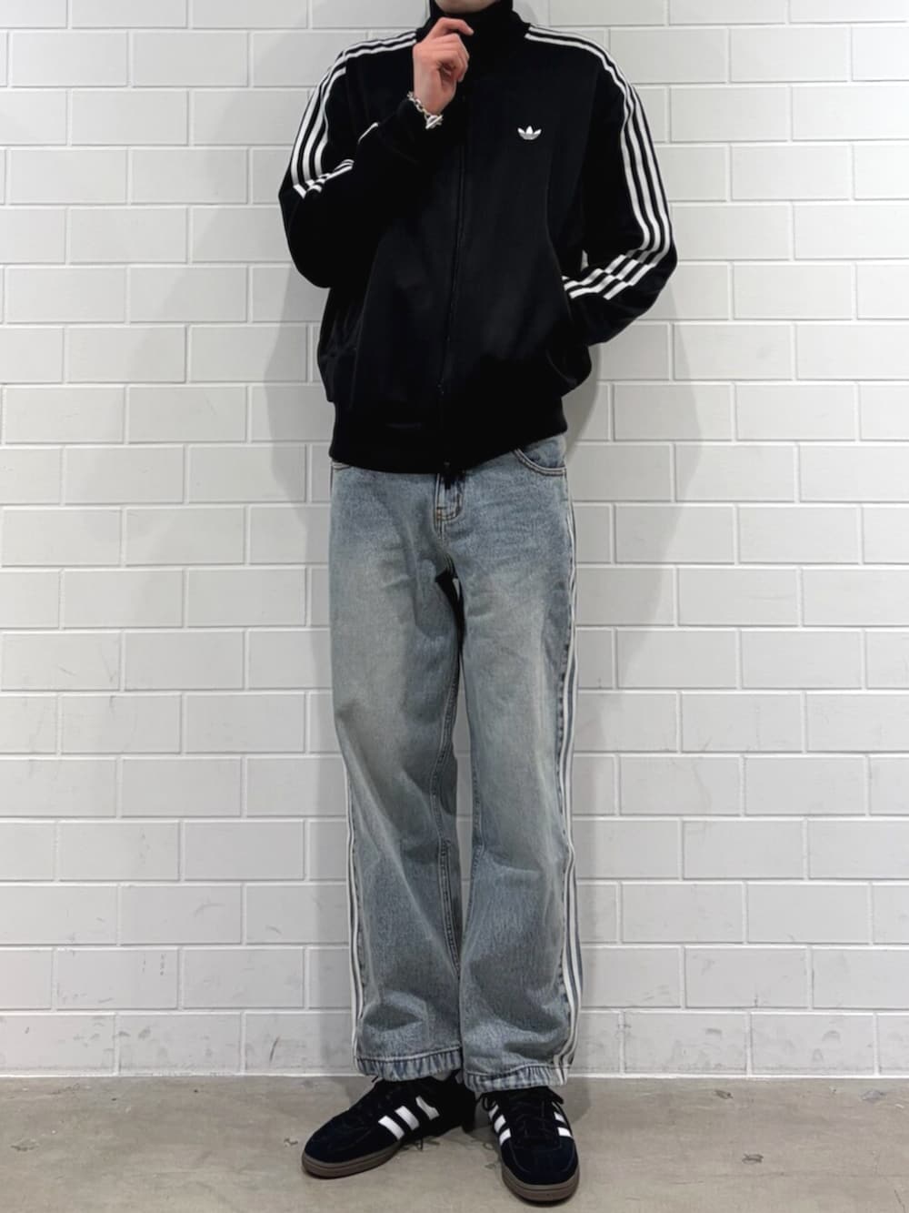 ブラック系のジャージ、ブラック系のスニーカー、ブルー系のデニムパンツを着用したメンズの春コーディネートの2枚目の写真