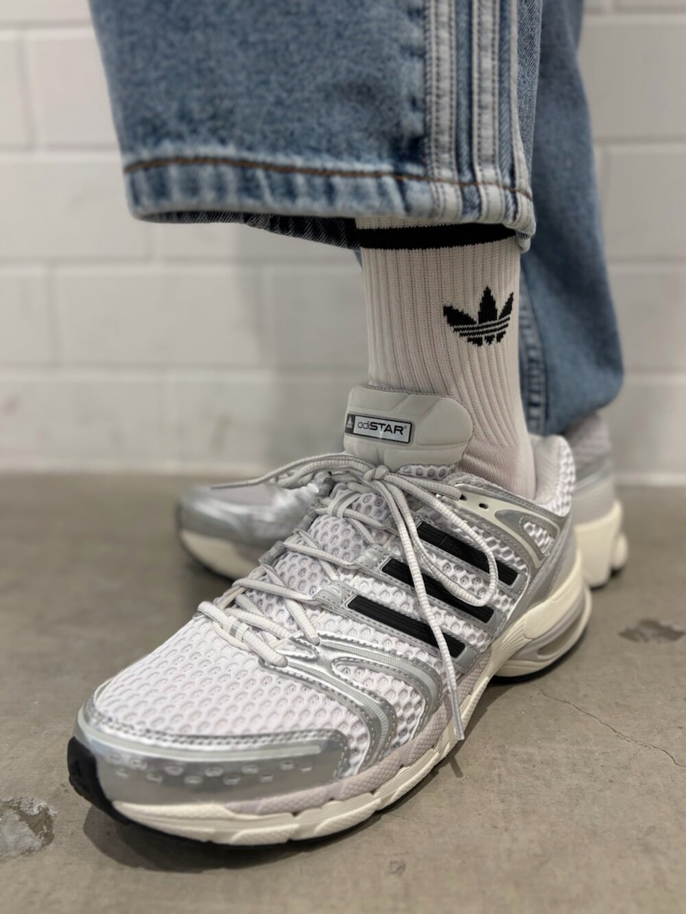 シルバー系のスニーカー、ブルー系のデニムパンツ、レッド系のジャージを着用したメンズの夏コーディネートの6枚目の写真
