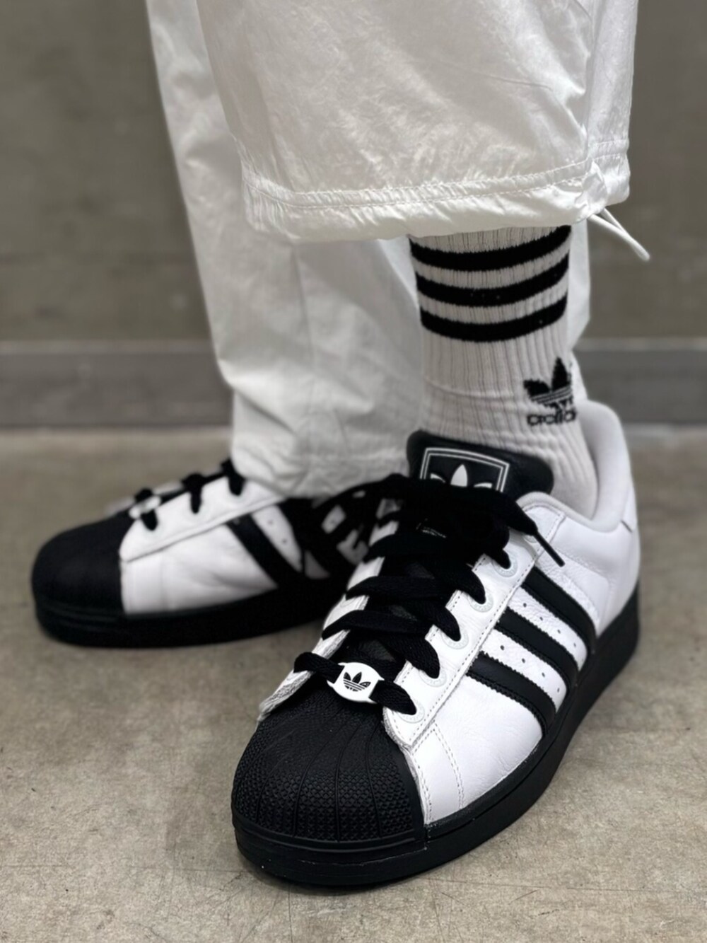 ホワイト系のスニーカー、ブラック系のTシャツ/カットソー、ホワイト系のその他パンツを着用したメンズの夏コーディネートの6枚目の写真