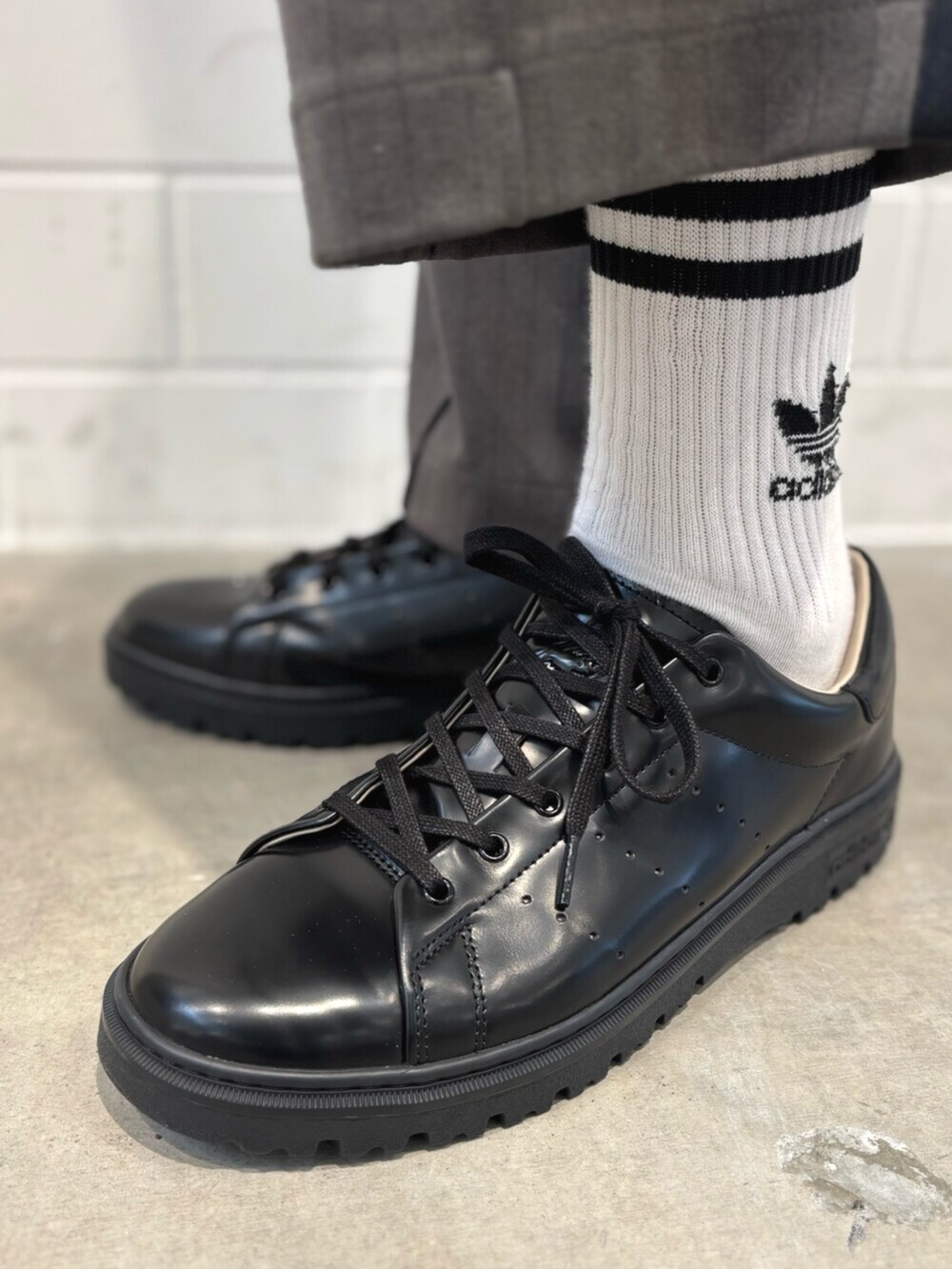 ホワイト系のポロシャツ、ブラック系のシューズ、グリーン系のスラックスを着用したメンズの秋コーディネートの6枚目の写真