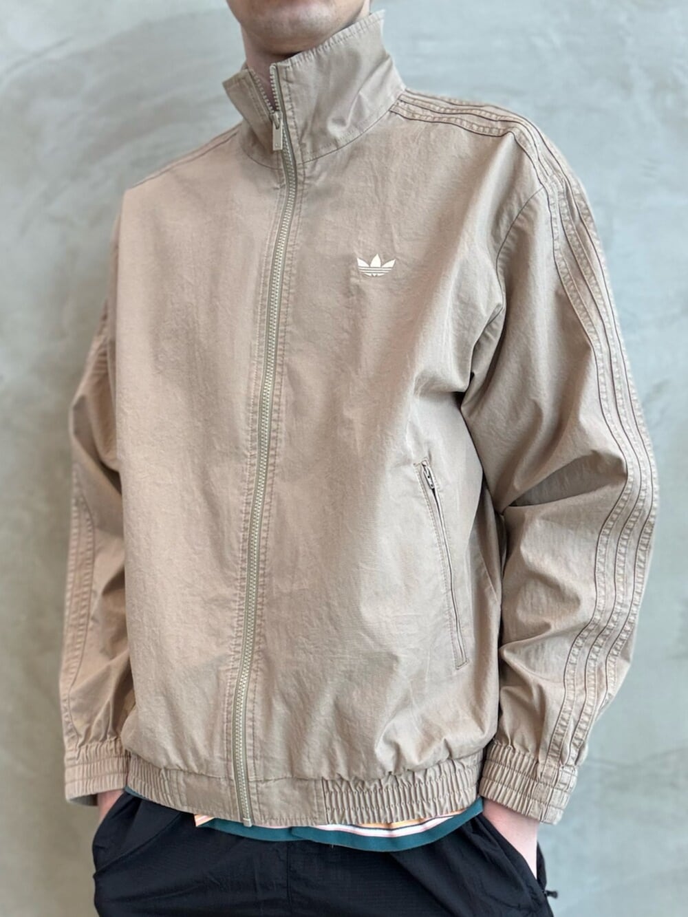 ホワイト系のスニーカー、ブラウン系のナイロンジャケット、ブラック系のその他パンツを着用したメンズの春コーディネートの3枚目の写真