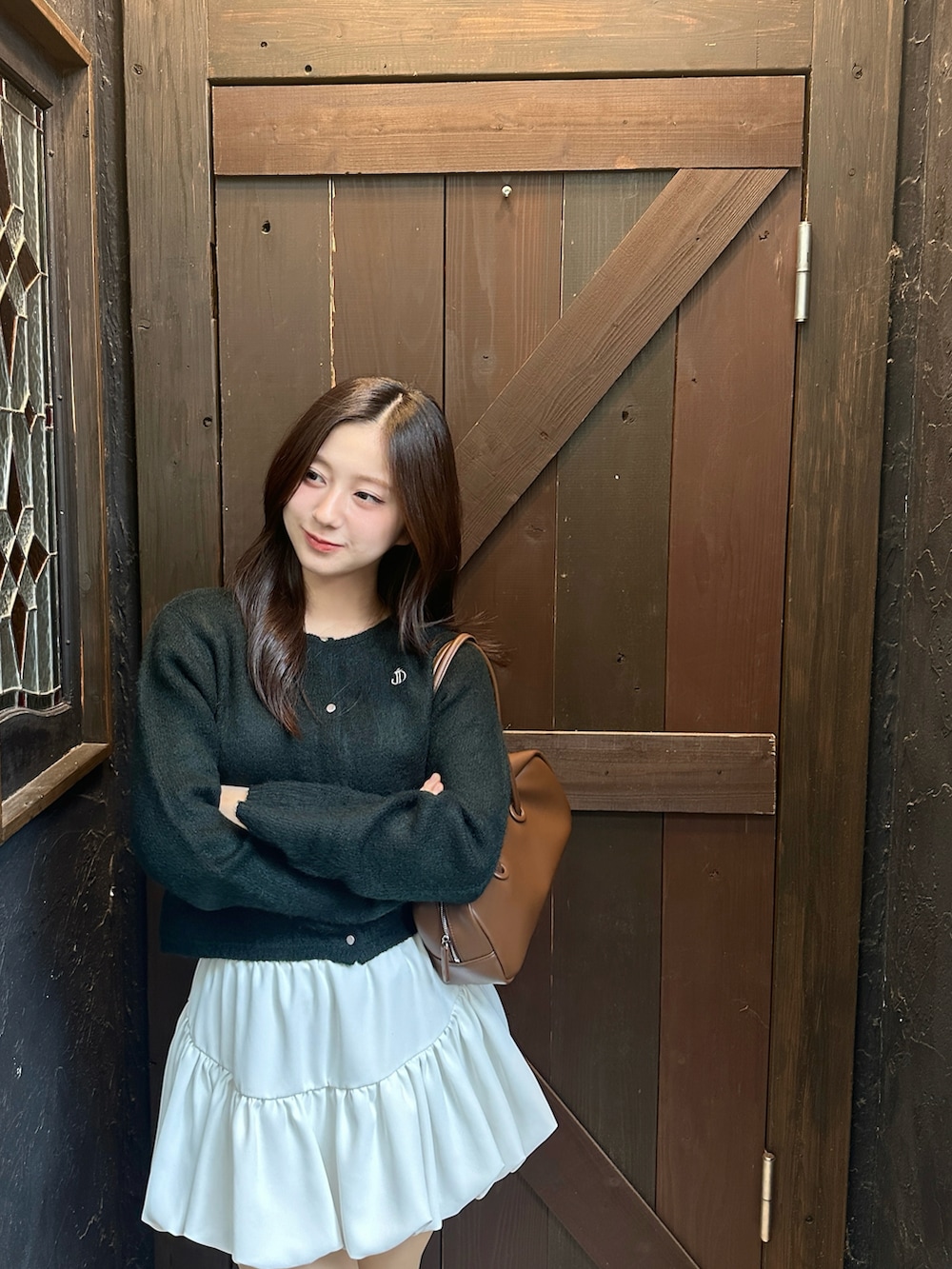 グリーン系のカーディガン/ボレロ、ホワイト系のスカート、ブラウン系のブーツを着用したレディースの冬コーディネートの2枚目の写真