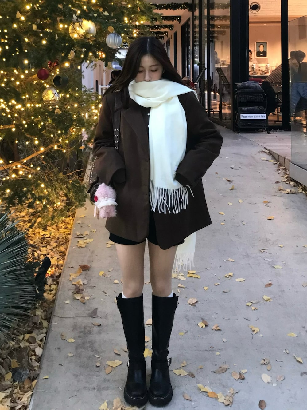 ブラック系のブーツ、ブラウン系のジャケット/アウター、ホワイト系のファッション雑貨を着用したレディースの冬コーディネートの2枚目の写真