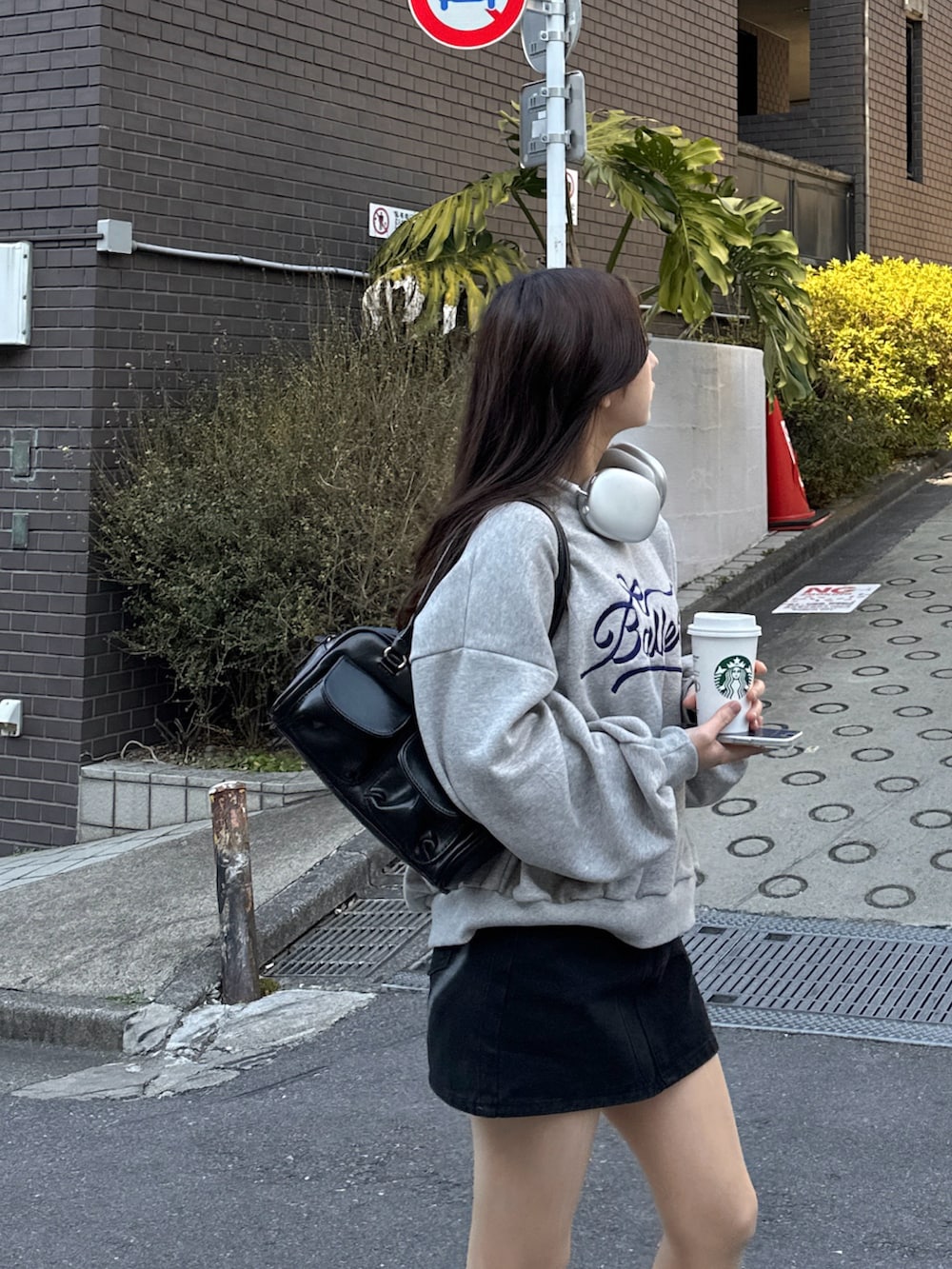 グレー系のスウェット、ブラック系のスカート、ベージュ系のスニーカーを着用したレディースの冬コーディネートの2枚目の写真