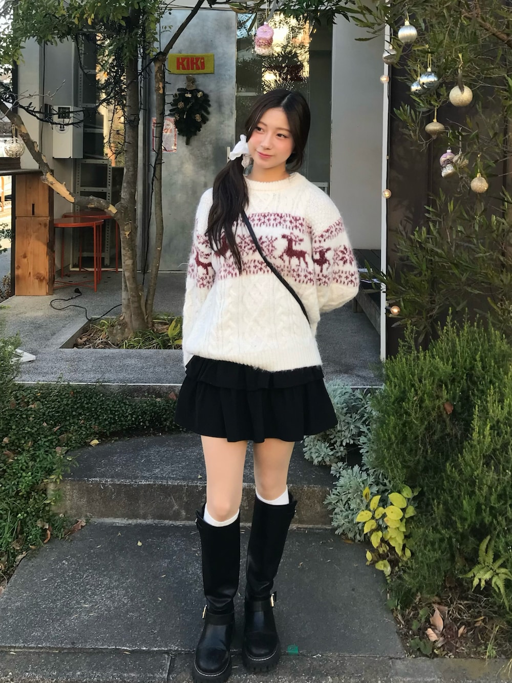 ホワイト系のニット/セーター、ブラック系のスカート、ブラック系のブーツを着用したレディースの冬コーディネートの2枚目の写真